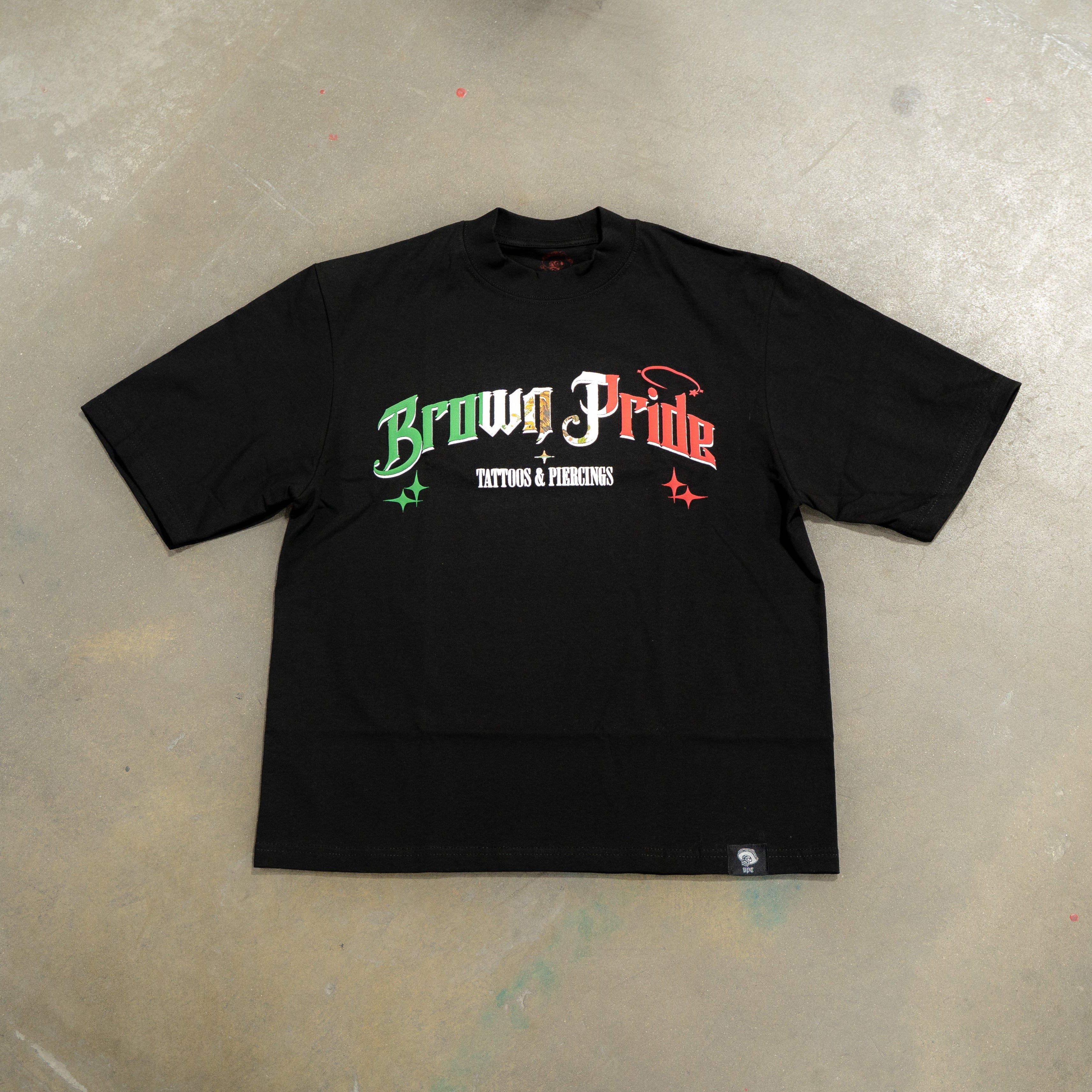 Black t-shirt with 'Brown Pride' text on a concrete floor