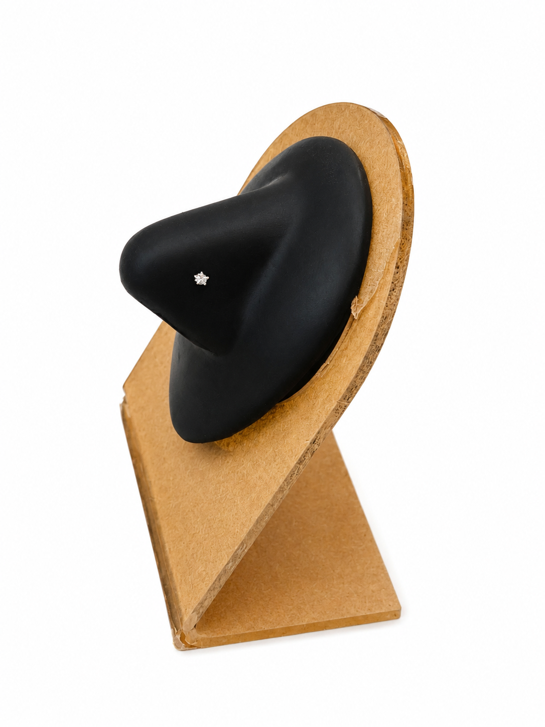 A black pointed hat with a small silver star detail, displayed on a light brown cardboard stand against a white background.